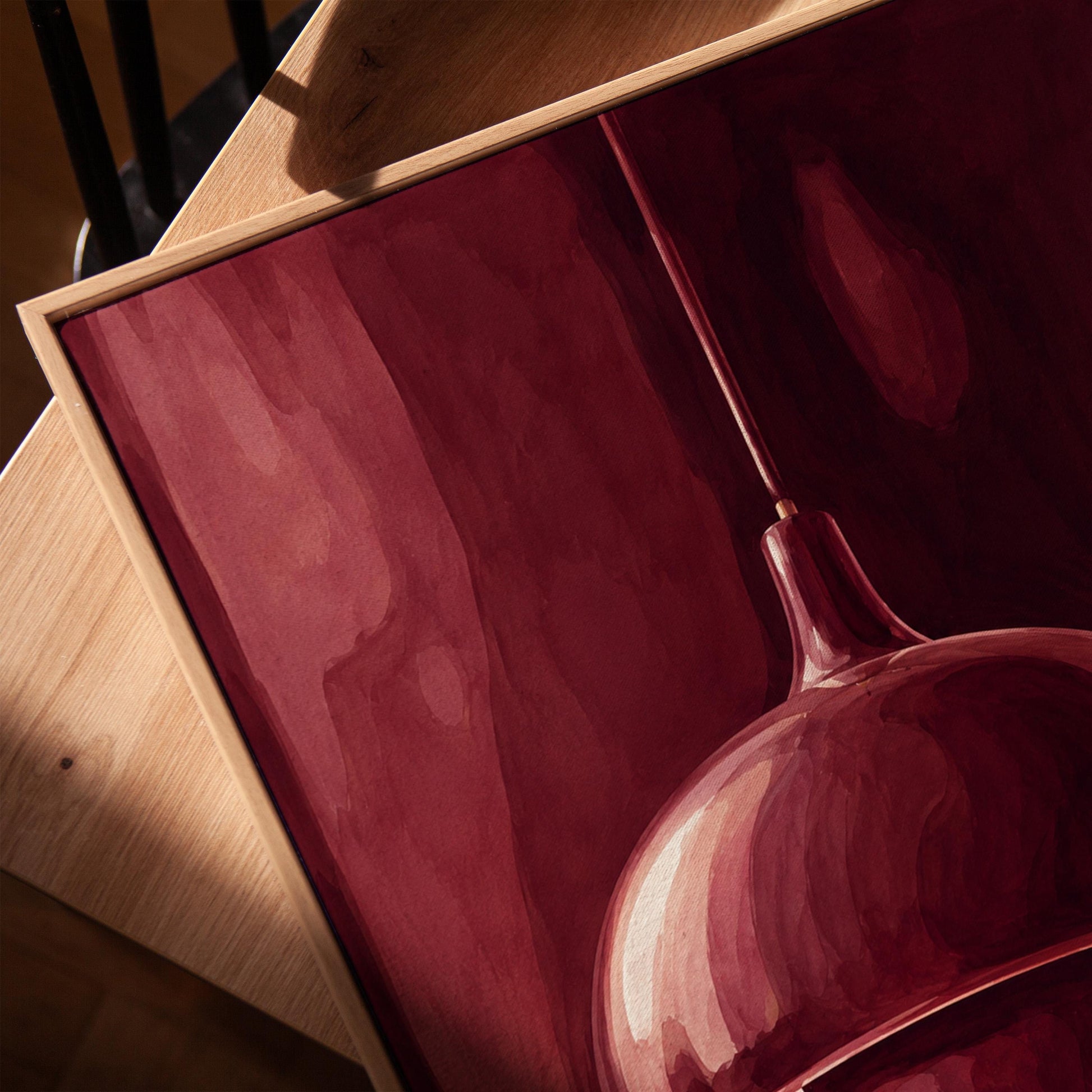 Pendant lamp glowing warmly against burgundy darkness, canvas print in a warm, minimally styled interior