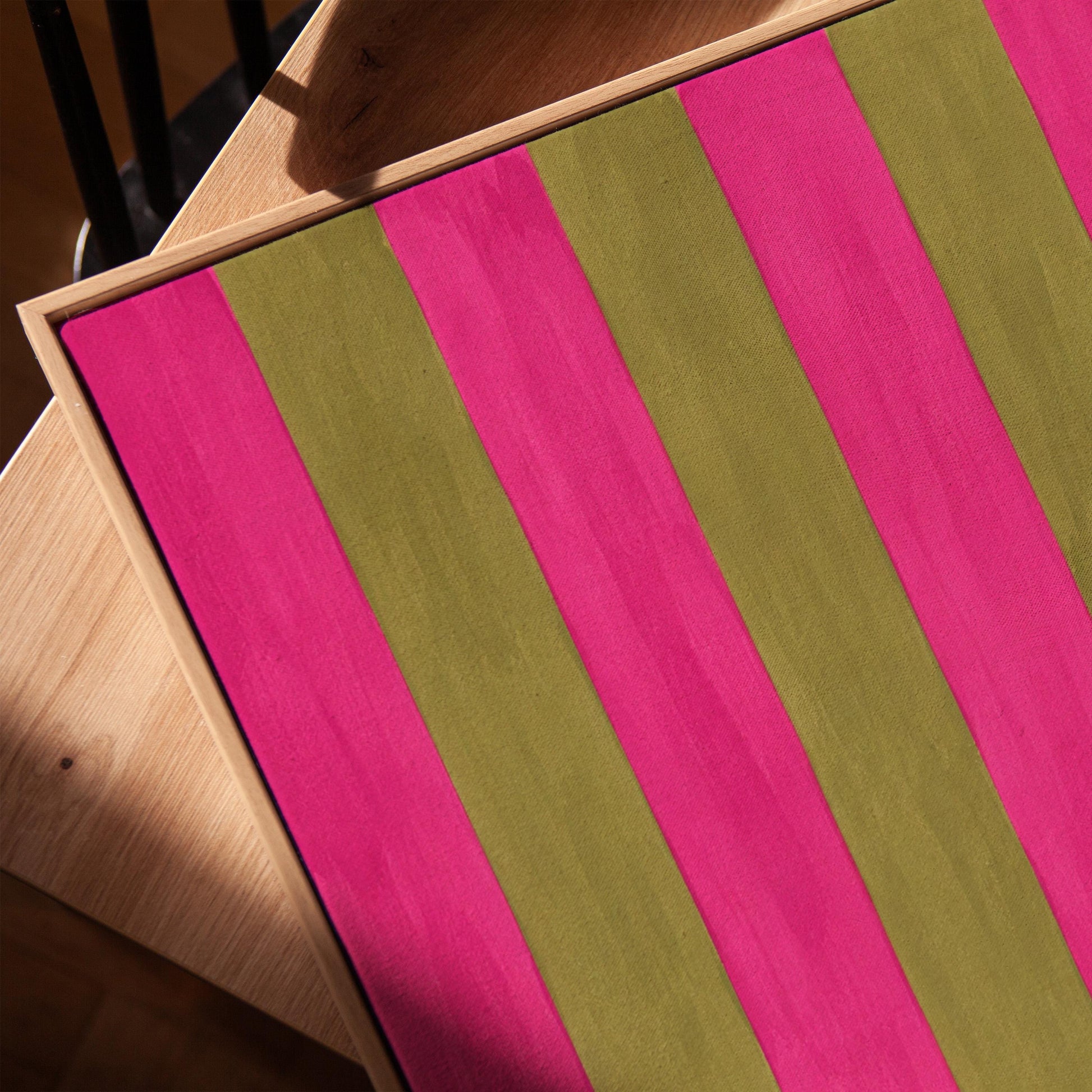 Bold vertical stripes in hot pink and olive green, canvas print in a warm, minimally styled interior